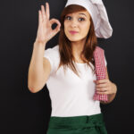 Young female cooking chef showing OK sign